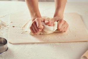 Woman kneading sourdough bread dough while learning how to homestead