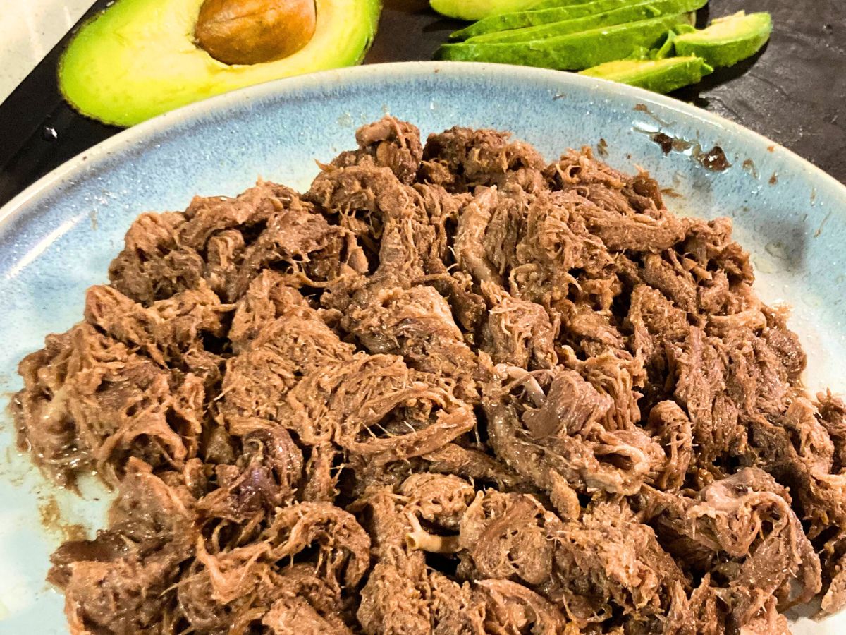 shredded beef tongue taco meat on a blue plate made in the oven