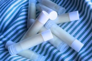 Nine tubes of DIY lip balm scattered on a green and white striped towel