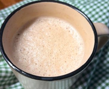frothy warm winter drink in a brown mug on a green and white checked towel