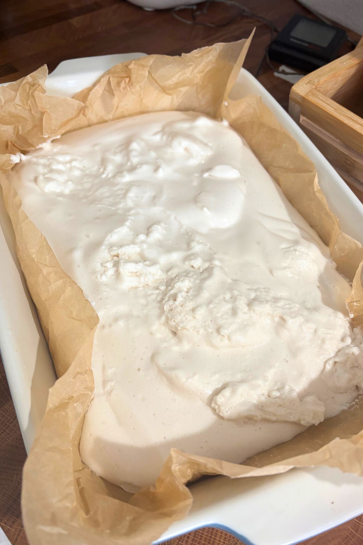homemade marshmallows spread in a white 9 by 13 pan that has been lined with parchment paper