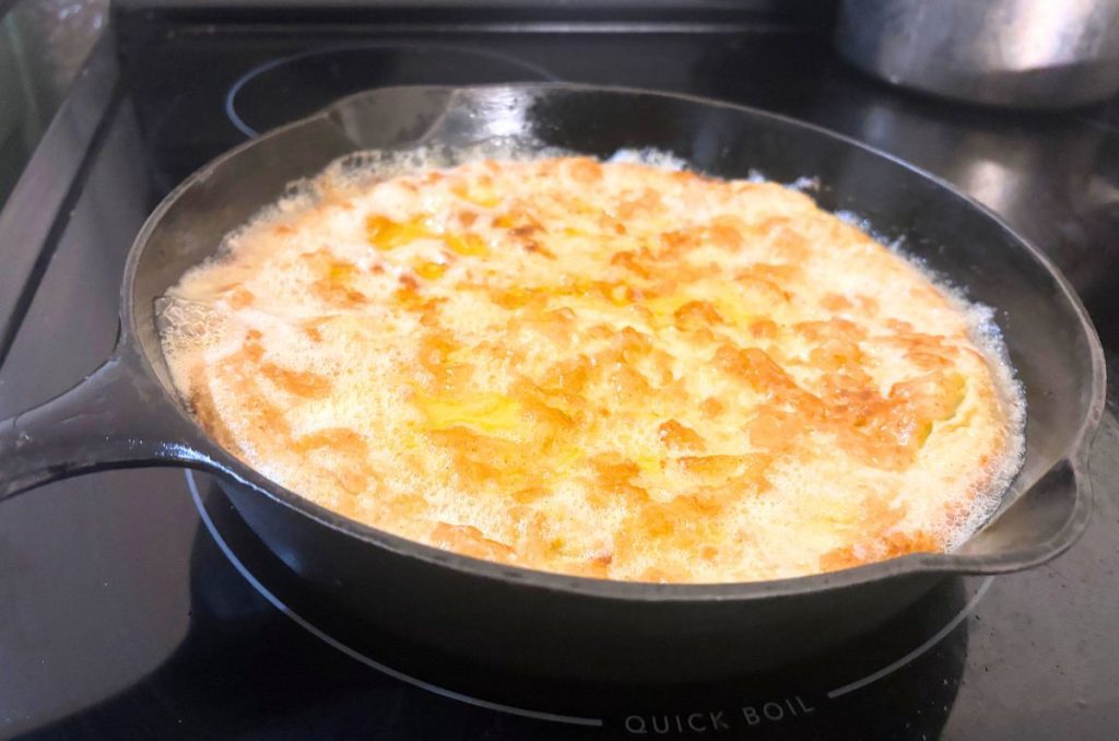 fresh milled gluten free sourdough oven pancake in a cast iron skillet on a black stove top