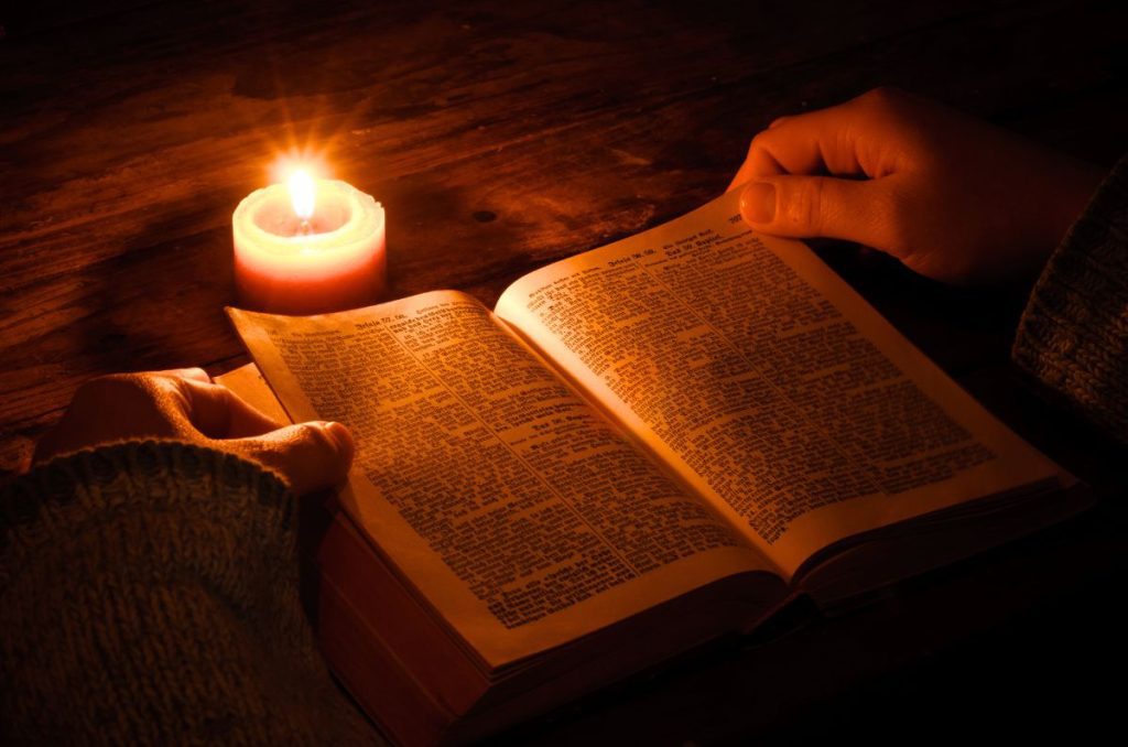 woman reading her bible by candle light studying God's truth about fertility