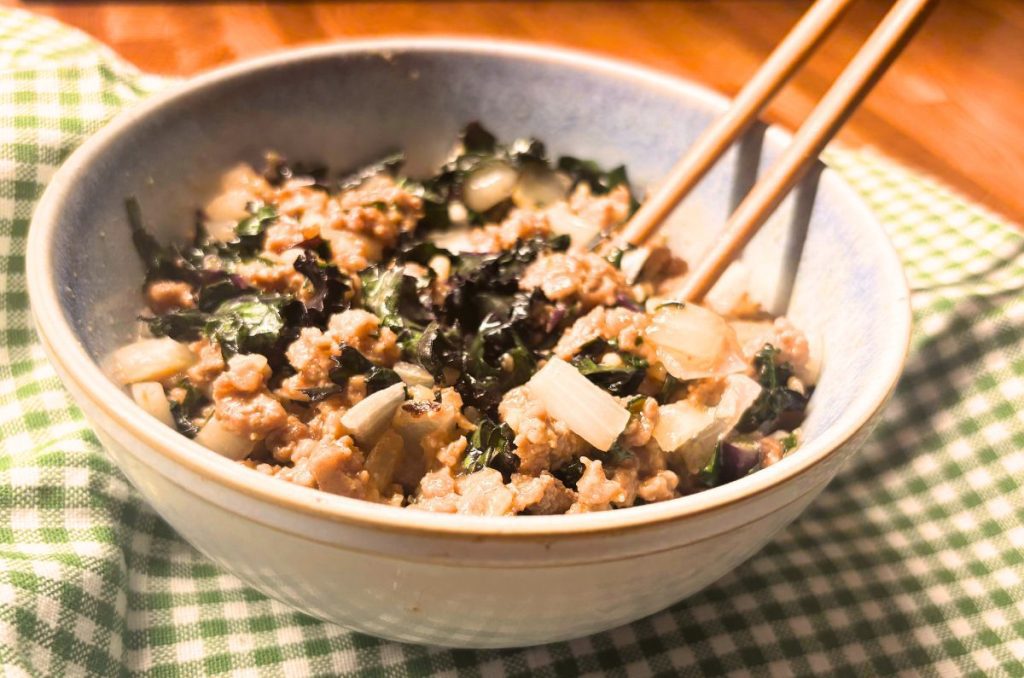 bowl of the best easy Pad Thai with kale and onions on a green checked towel