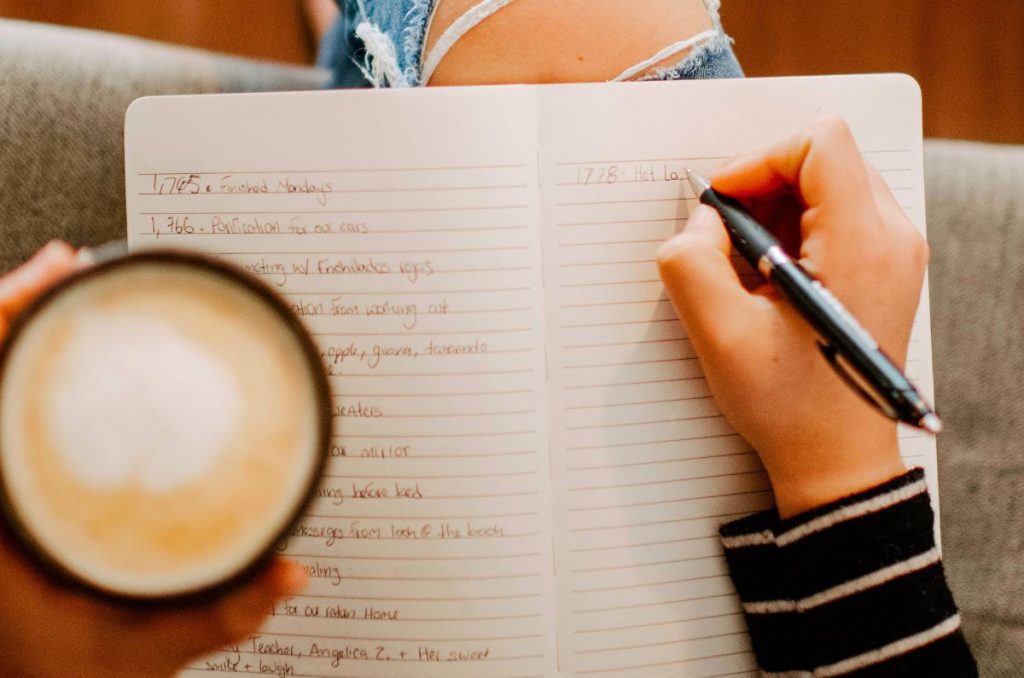 woman practicing slow living with a journal in her lap and a mug with a latte