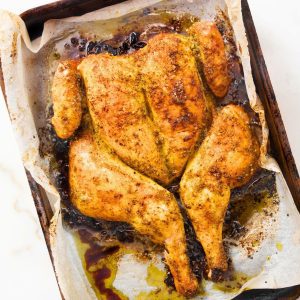whole oven roasted chicken on a baking sheet with parchment paper