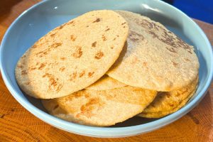 several homemade flour tortillas stacked on a blue plate