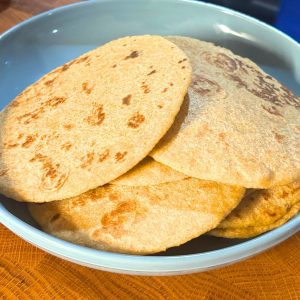 several homemade flour tortillas stacked on a blue plate