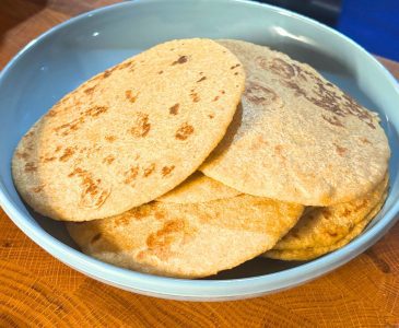 several homemade flour tortillas stacked on a blue plate