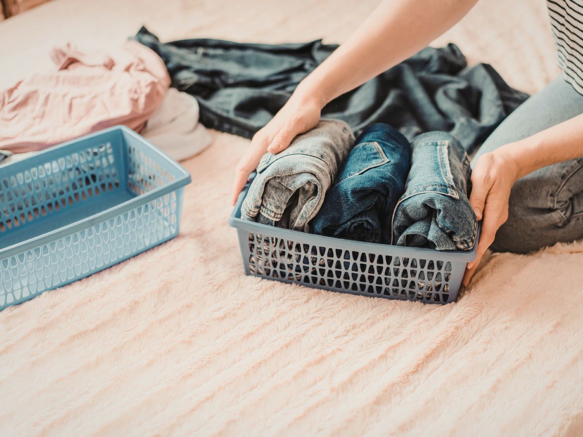 woman decluttering and organizing her wardrobe with clothes and baskets on her bed