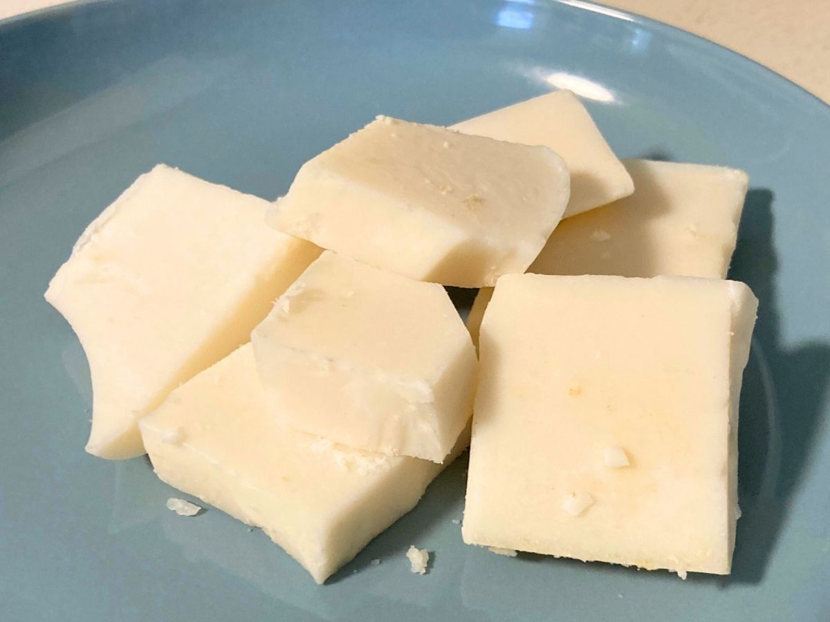 Rendered grass-fed tallow chunks for making homemade tallow body butter lotion on a blue plate