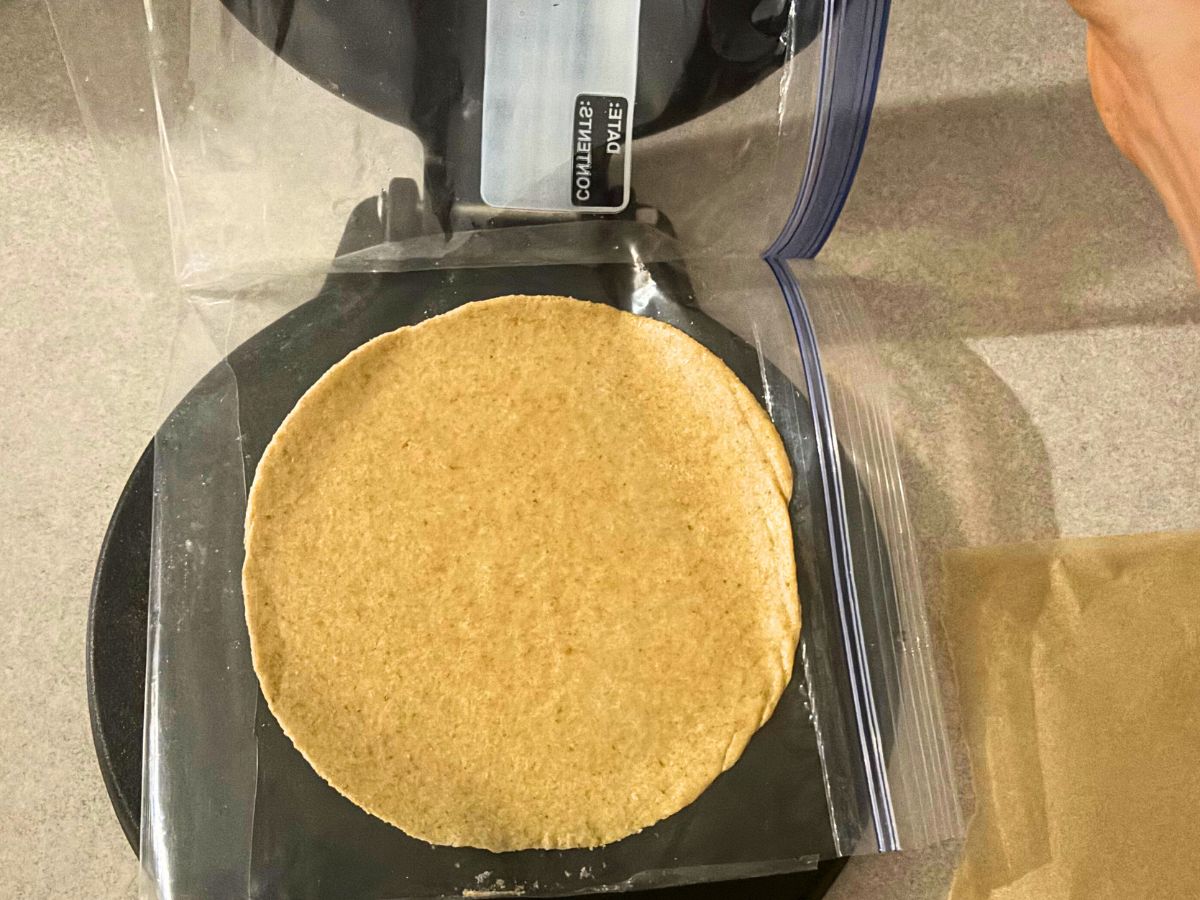 homemade flour tortilla made with freshly milled flour being flatten in a black cast iron tortilla press