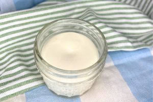 homemade non-toxic beef tallow sunscreen in a two ounce mason jar sitting on top of green, blue, and white towels