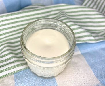 homemade non-toxic beef tallow sunscreen in a two ounce mason jar sitting on top of green, blue, and white towels