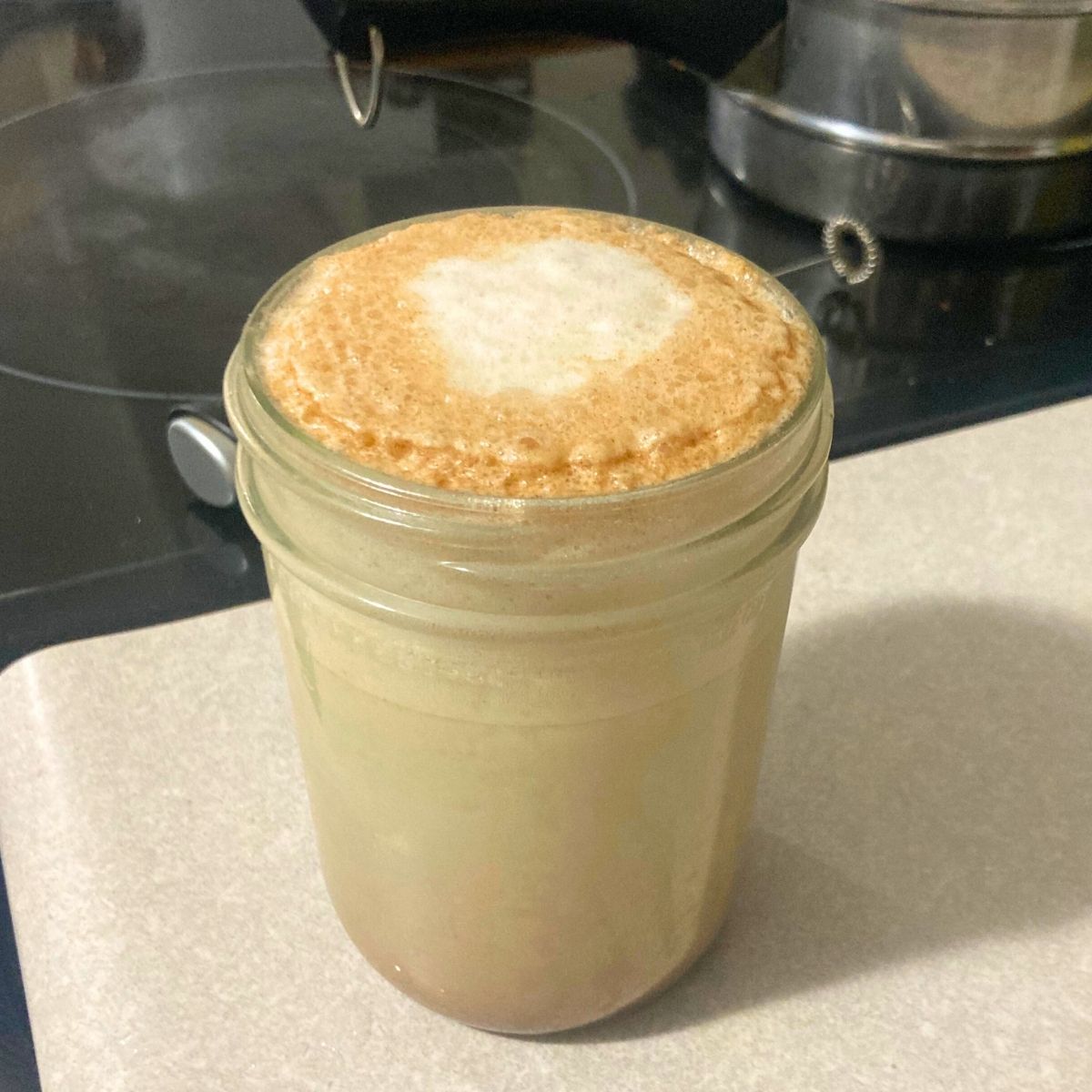 mason jar filled with coffee and milk with a creamy foam on top