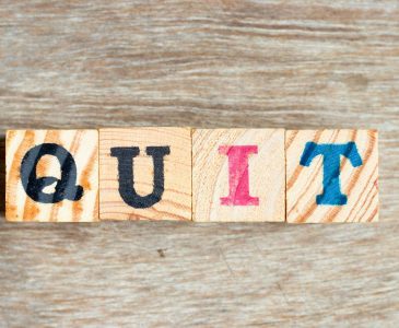 four wooden blocks with the word quit spelled out in hand drawn letters