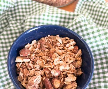 navy blue bowl filled with homemade cinnamon roll granola sitting on a green checked towel