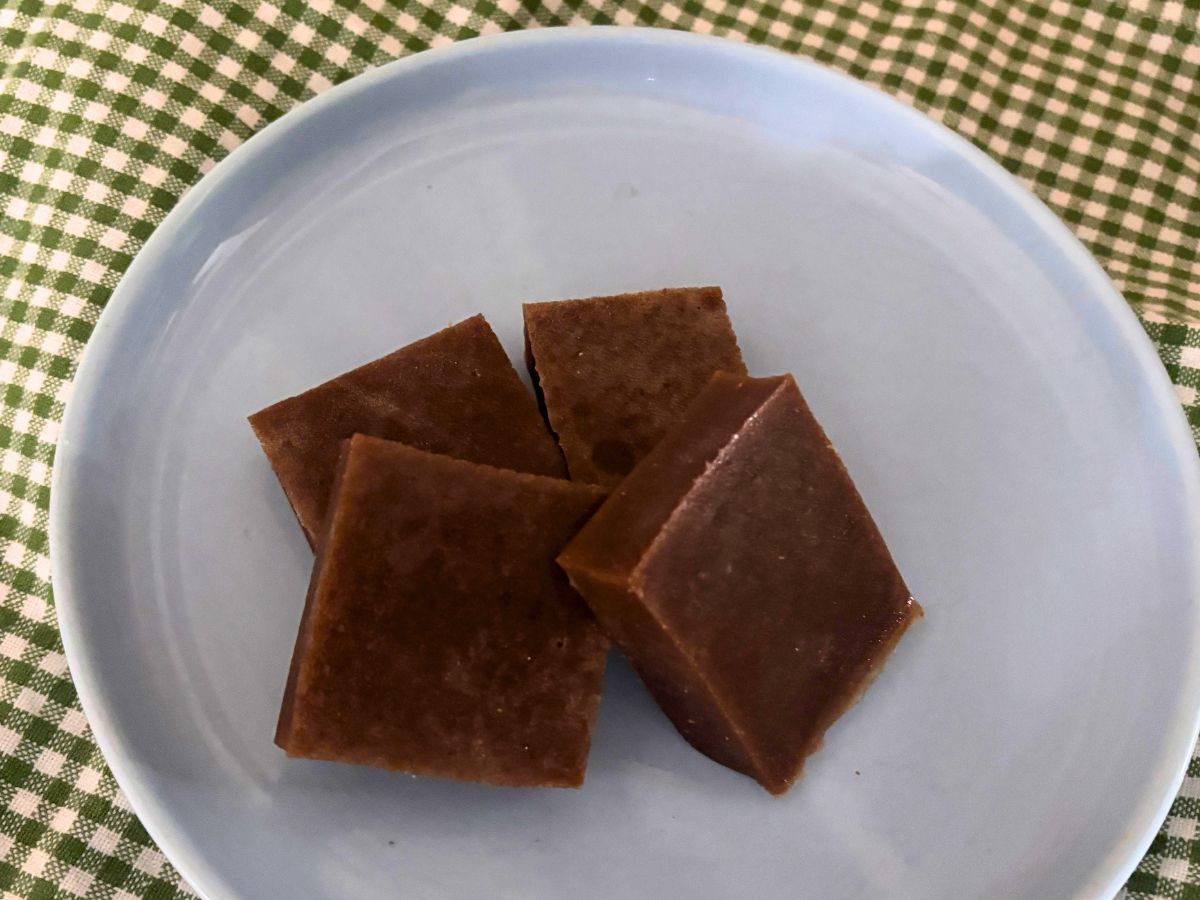 homemade grape beef gelatin gummy candies on a light blue plate on top of green and white checked tea towel