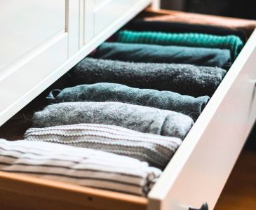 clothing of a capsule wardrobe neatly folded in a white dresser drawer