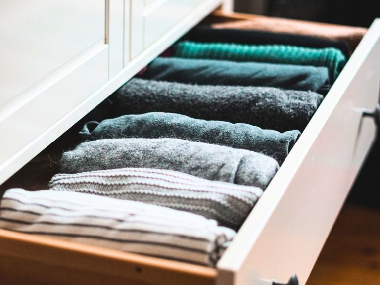 clothing of a capsule wardrobe neatly folded in a white dresser drawer