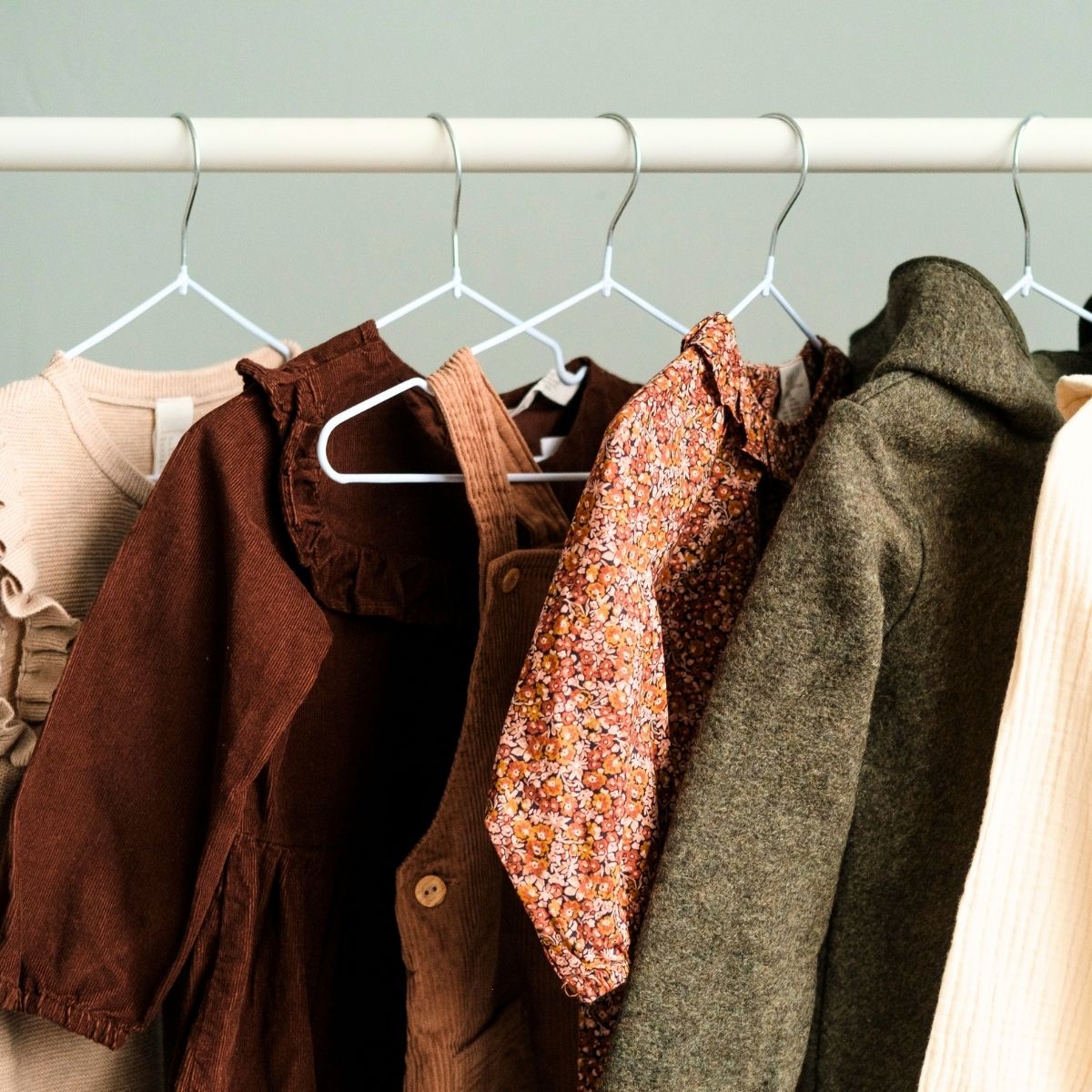 minimalist closet with six items of clothing hanging from a white bar