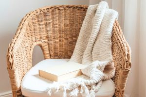 minimalist wicker chair with a white cushion and a white blanket draped over the back