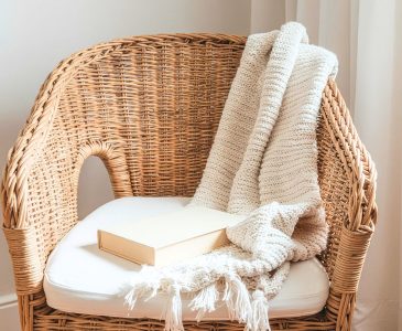 minimalist wicker chair with a white cushion and a white blanket draped over the back