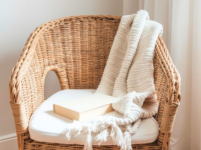 minimalist wicker chair with a white cushion and a white blanket draped over the back