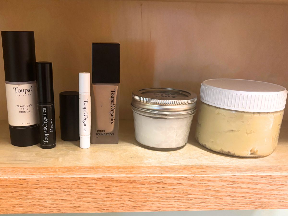 minimalist non-toxic skin care products such as makeup cleanser and moisturizer sitting on a wooden bathroom shelf